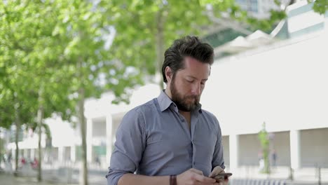 Man-walking-on-street-and-texting-via-smartphone
